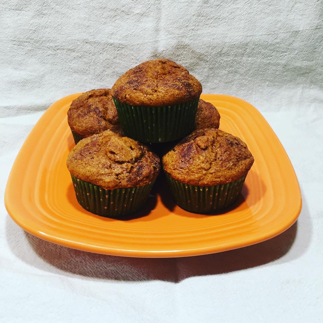 pumpkin spice muffins on an orange plate with white fabric background